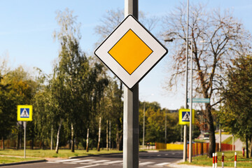 Main road priority traffic sign in city. Street safety rules in Poland. Urban transportation and driving concept. Crossroad with road signs. Safety on streets and transport regulations.