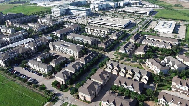 Cypress Waters master planned community showing townhomes, apartment buildings, office structures, tree-lined streets, green buffers, capturing suburban planning and land use integration, Texas