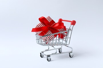 A miniature shopping cart and red gift box on a white background, Black Friday or holiday shopping