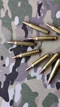 Machine gun cartridges on a camouflage background, military wallpaper. Camouflage background as a backdrop for your design