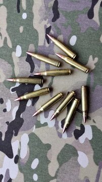 Machine gun cartridges on a camouflage background, military wallpaper. Camouflage background as a backdrop for your design