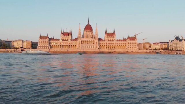 Hungarian parliament building gleams along the danube river at sunset