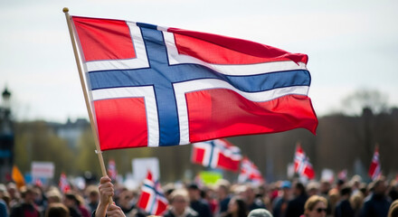 Hand holding a Norway flag waving in the air. People celebrate national day. May 17th concept.