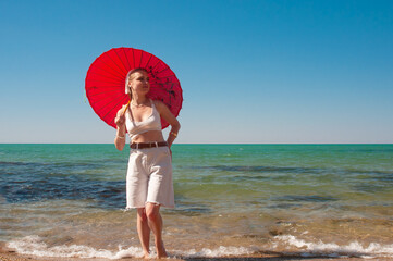 Girl with red umbrella on a sea shore