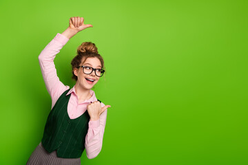 Cheerful young woman in casual attire pointing excitedly to the side against a vibrant green background, showcasing enthusiasm