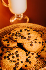 Warm chocolate chip cookies on a cozy table with a glass of milk