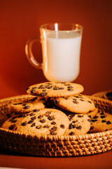Freshly baked chocolate chip cookies with a glass of milk on a warm background