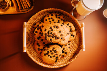 Freshly baked cookies served in a woven basket with a glass of milk on a warm table