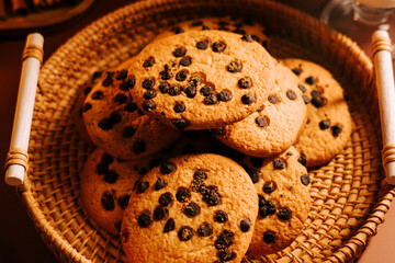 Freshly baked chocolate chip cookies in a woven basket on a wooden table