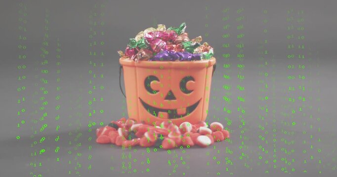 Green binary code streaming over jack-o'-lantern bucket and candy corn then fading to reveal scene