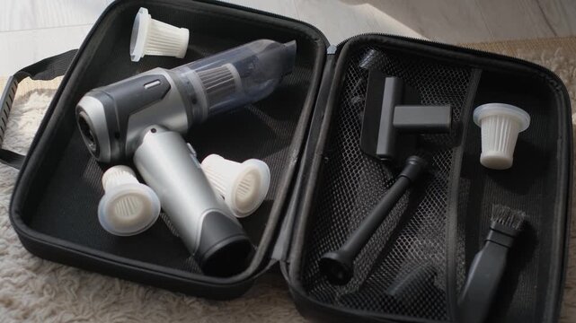 A close-up of a compact cordless vacuum cleaner and accessories in an open case