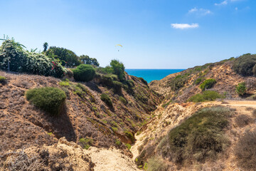 Steep cliffs rise above the azure coast of the Mediterranean Sea. The sea and the sky merge in soft shades of blue