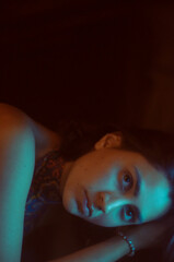 Fototapeta premium retrato oscuro de mujer con iluminacion cian y naranja