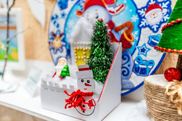 A white plate with a snowman on it sits on a shelf next to a Christmas tree