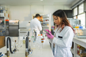 Obraz premium Focused female scientist working with smartphone in modern university laboratory