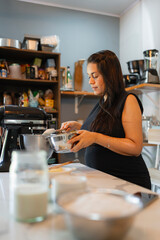 Pregnant woman preparing food in kitchen using electric mixer