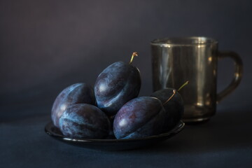 Arrangement with blue purple plums on a background of the same color