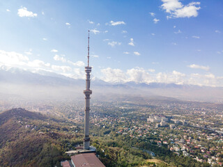 Fototapeta premium Late September in Almaty, a drone view of the Kok-Tobe TV tower. The city and mountains, yellowed grass and foliage are visible. An autumn landscape.