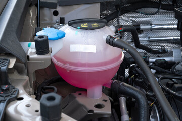 Car coolant tank. Pink liquid in the tank.