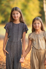Fototapeta premium Portrait of two beautiful dressed children sisters outdoors.