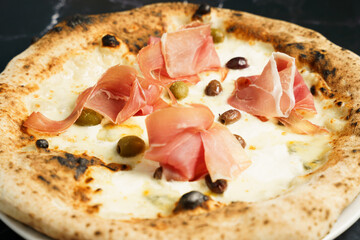 Artisan pizza with prosciutto and olives