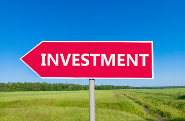 Investment symbol. Concept word Investment on beautiful red road sign. Beautiful blue sky green grass and forest peaceful nature background. Business investment concept. Copy space.