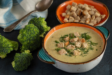 Broccoli cream soup with greens and crackers on an oak tray. Healthy food rich in vitamins, trace elements and fiber. Vegetarian food.