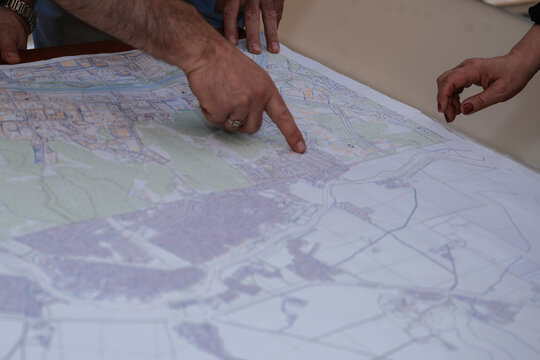 Group examines detailed map at planning session for local development project in community setting during the afternoon