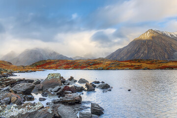 Mountain lake and mountain peaks with low clouds.
