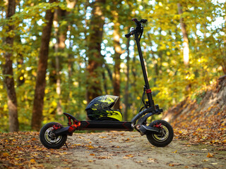 A powerful modern electric scooter stands on a path in an autumn forest.