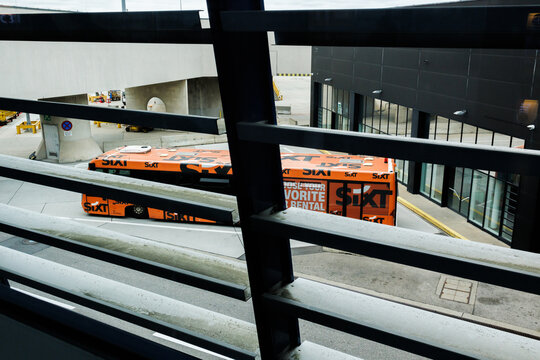 Vienna, Austria. September 23, 2025. Editorial stock photo. An orange shuttle bus branded with a SIXT car rental company logo waits at the airport terminal.