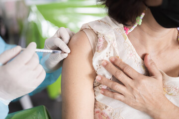 Healthcare worker in gloves administering vaccination or injection into a patient's upper arm....