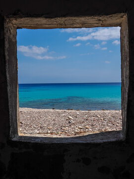 Scenic view of the turquoise Arabian Sea through a rustic stone window frame on the coast of Socotra Island