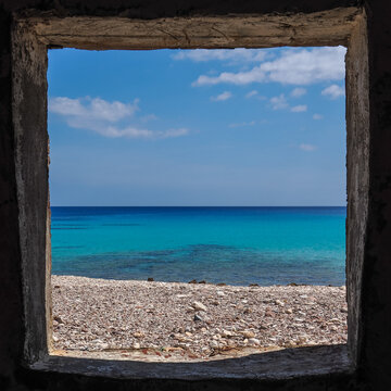 Beautiful turquoise sea and sky seen through square window frame with beach in foreground, Socotra Yemen
