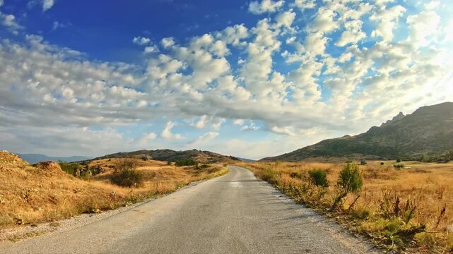 Travel, rolling countryside, golden dry grass nature, sparse clouds sky, POV