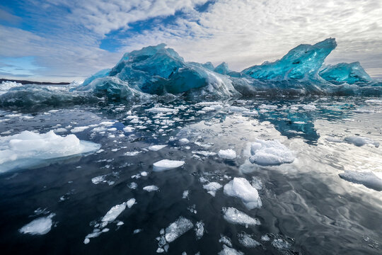 Blue Diamond Iceberg Floating in the Water with Dramatic Sky at J&ouml;kuls&aacute;rl&oacute;n Glacier Lagoon, Iceland.