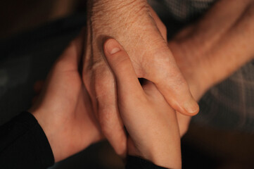 Fototapeta premium Close-up of several hands of different ages stacked together, symbolizing family, unity, support, and connection across generations. 