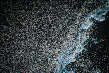 Abstract view of white and blue particles floating against a black background, resembling stars in space or underwater bubbles in darkness.