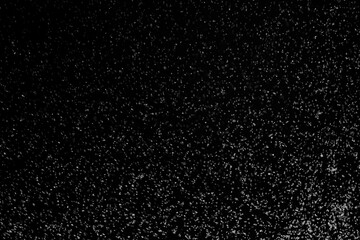 Black and white abstract image resembling snowfall at night or a starry sky, with countless white specks scattered across a dark background.