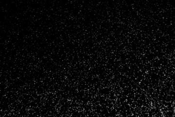 Obraz premium Black and white abstract image resembling snowfall at night or a starry sky, with countless white specks scattered across a dark background.