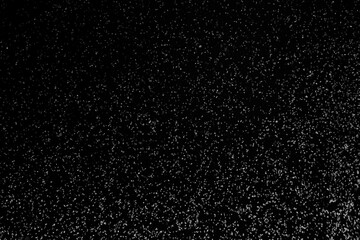 Black and white abstract image resembling snowfall at night or a starry sky, with countless white specks scattered across a dark background.