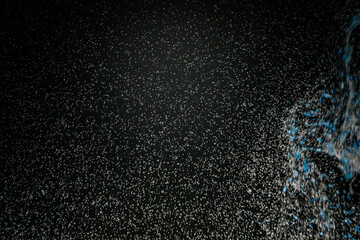 Abstract view of white and blue particles floating against a black background, resembling stars in space or underwater bubbles in darkness.
