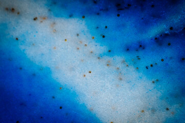 Abstract image in deep blue shades with black specks, resembling an ocean wave, galaxy swirl, or cosmic nebula with flowing textures.