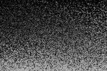 Black and white abstract image resembling snowfall at night or a starry sky, with countless white...