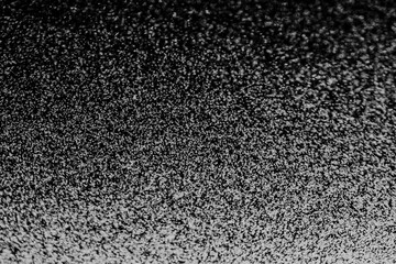 Black and white abstract image resembling snowfall at night or a starry sky, with countless white...