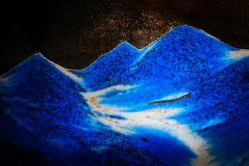 Abstract image resembling a blue ocean wave or mountain range with white and black textures,...