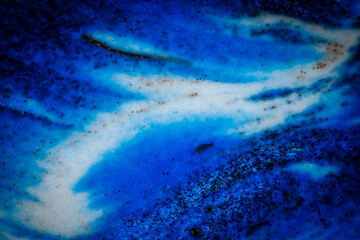 Abstract image in deep blue shades with black specks, resembling an ocean wave, galaxy swirl, or cosmic nebula with flowing textures.