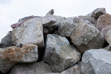 Pile of large natural rocks with rough textures in neutral colors against the sky