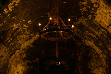 Old stone cellar features rustic chandelier and dim lighting creating a cozy, mysterious atmosphere perfect for gatherings or events © Akshatha
