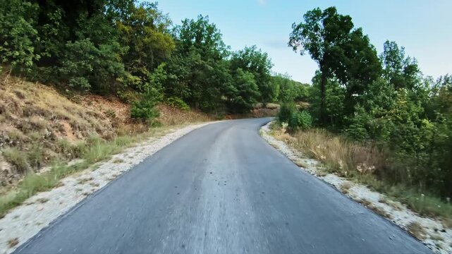 Curvy road across high forested area, summer time, POV driver point of view